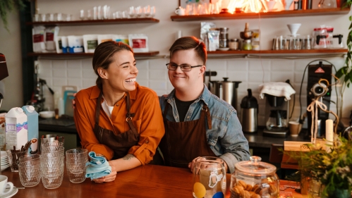 a man and woman at the counter of a coffee shop smiling