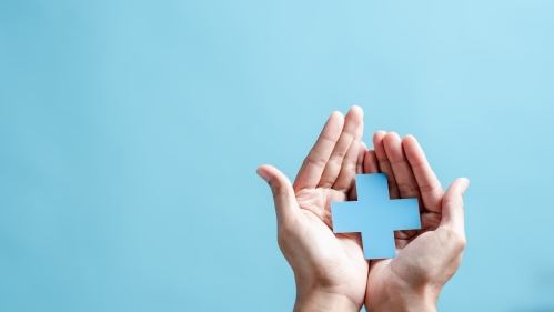 hands on a light blue background holding a plus symbol of the same shade of blue